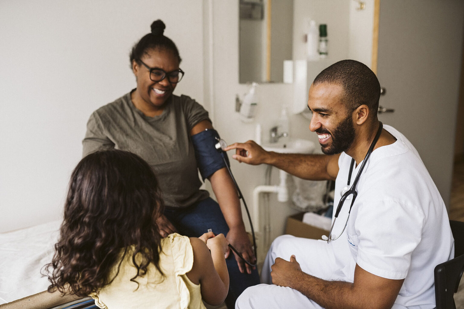 Doctor checking blood pressure with mother and child present